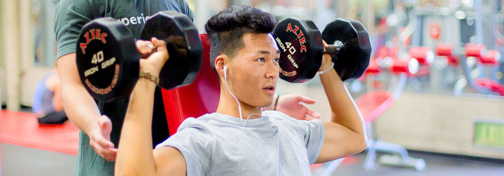 Student weight training on a seating bench with free weights